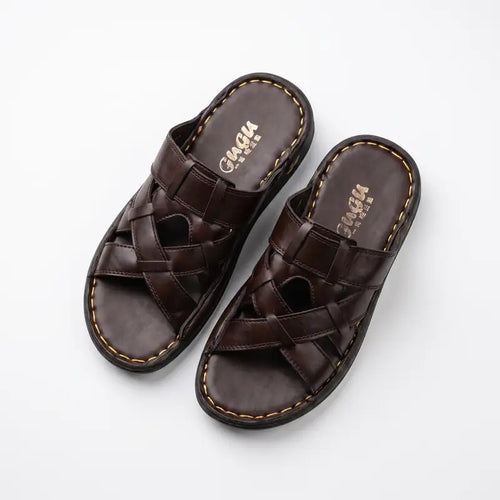 A pair of dark brown leather slide sandals with woven crisscross straps and contrast stitching, displayed on a clean white background. The brand name 'CAGIA' is visible on the footbed.