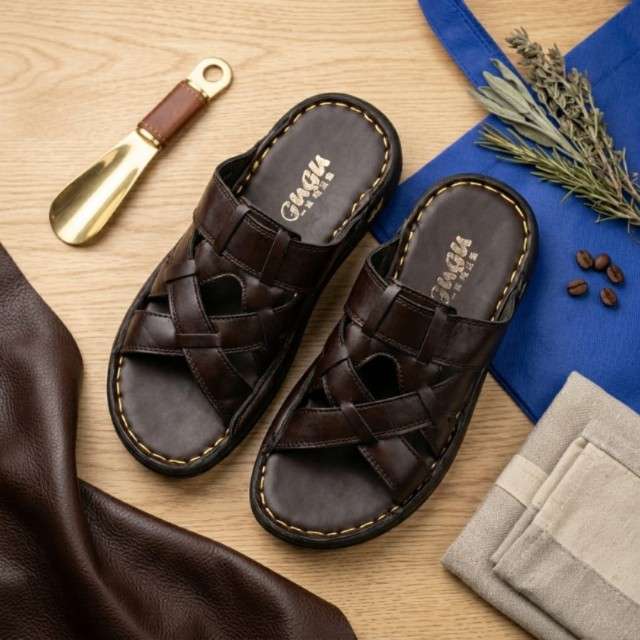 Pair of brown sandals with 'Cushion' branding on a wooden surface with a shoe horn and herbs.