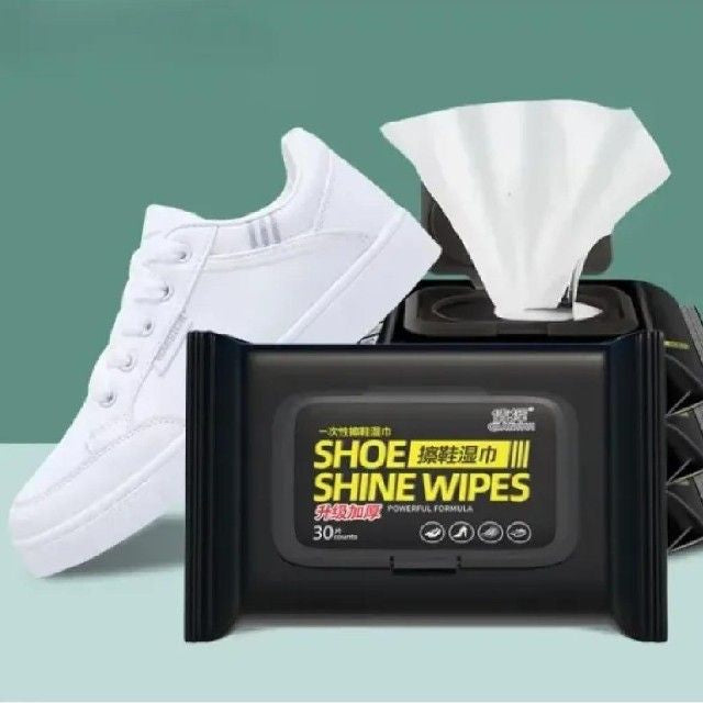 Black packaging of shoe shine wipes with a white sneaker and tissue on a green and blue gradient background