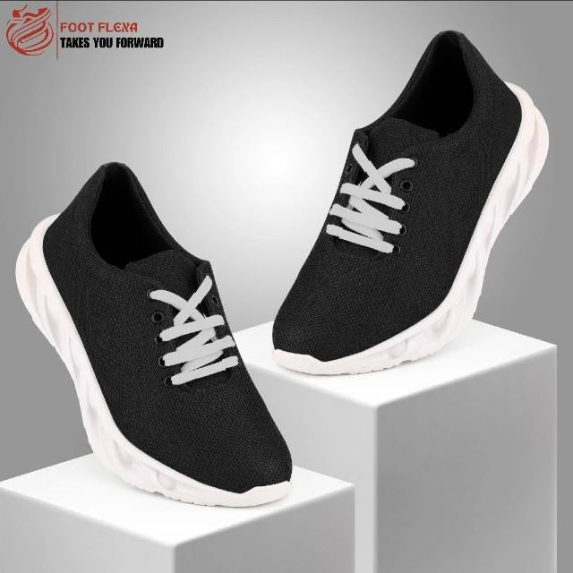 Black running shoes with white laces on a gray background, featuring the 'Foot Flexa' brand.