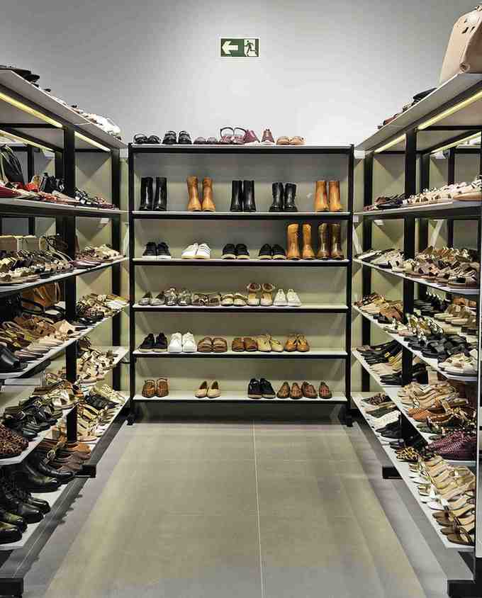 Shoe store with shelves filled with various shoes on a gray floor.